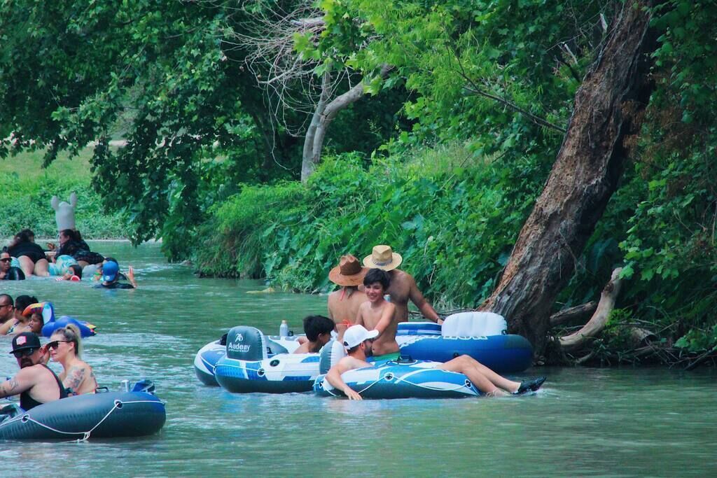 People on inflatable rafts in a river surrounded by greenery.