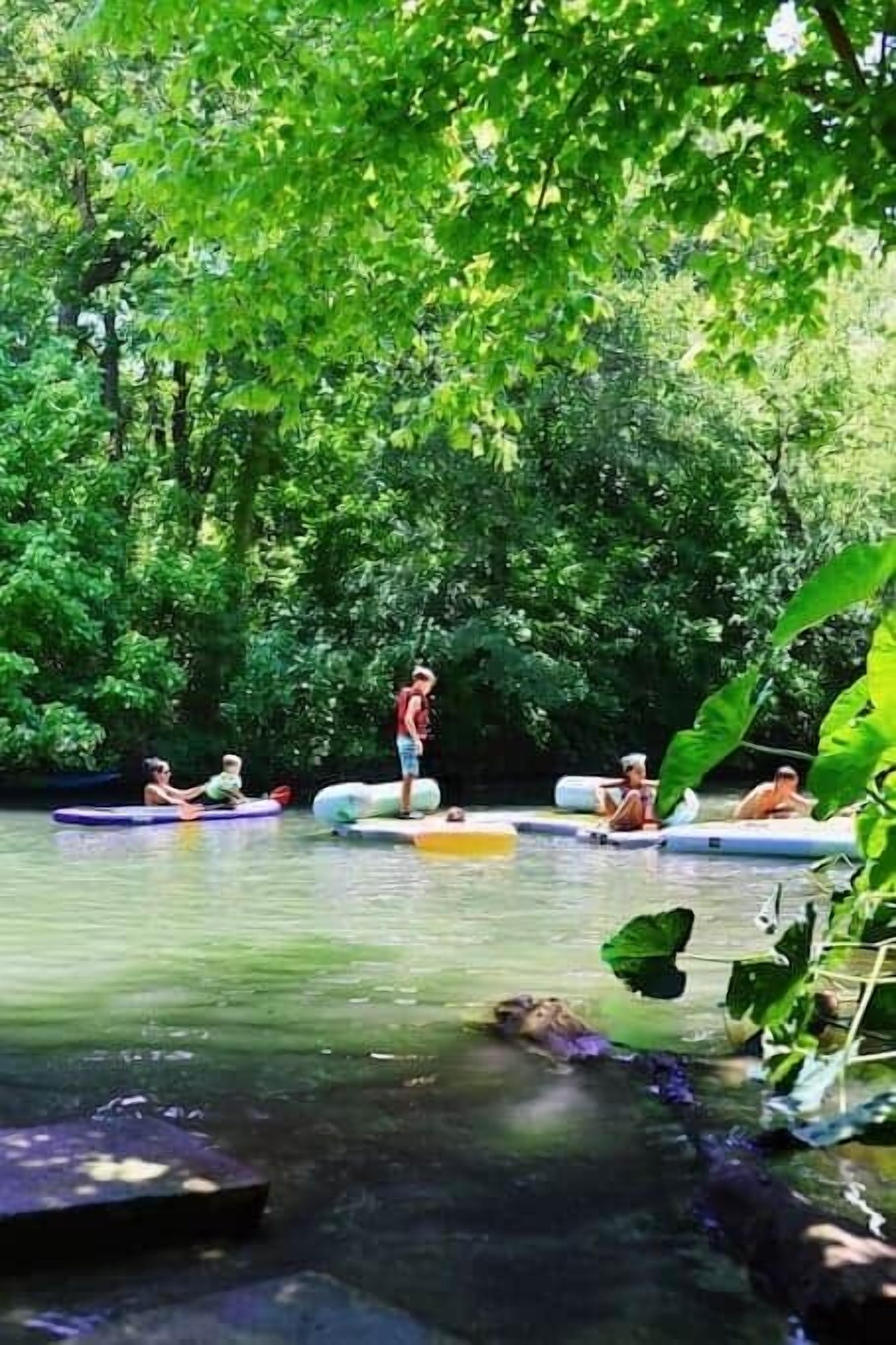 A group of people on inflatable rafts in a forested area with a calm river.