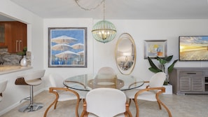 Uma sala de jantar moderna com uma mesa de vidro, cadeiras de madeira e um lustre.