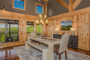 A wooden interior with a dining table, benches, and a chandelier. - Splashing at the Bluffs (Sevierville)