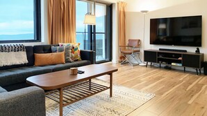 Una sala de estar moderna con sofá, mesa de centro, televisor y balcón con cortinas.