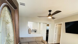 A modern living room with a sectional sofa, a glass coffee table, and a TV mounted on the wall. - Cute 2 bedroom in the heart of Houston  (Houston)