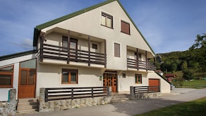 Un edificio de dos pisos con techo inclinado, balcones de madera y base de piedra.