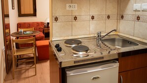 Cocina pequeña con armarios de madera, estufa integrada, un lavamanos y un refrigerador compacto.