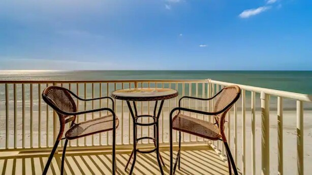 A balcony with a view of the beach and ocean.