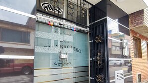 Een hotelingang met een glazen deur, een metalen hek en een geruit vloerpatroon.