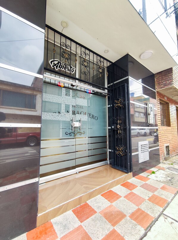 A hotel entrance with a glass door, metal gate, and a checkered floor pattern.