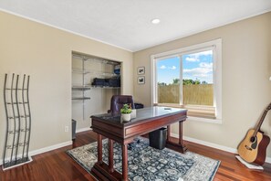 Enjoy a peaceful retreat with a view of the outdoors from the large window, a comfortable workspace at the desk, and a guitar for your musical inspiration.