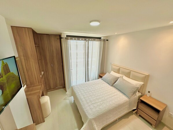 Quarto moderno com cama, mesa de cabeceira, guarda-roupa e televisão.