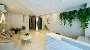 A modern hotel lobby with a reception desk, seating area, and a wall-mounted plant. - COMODO MONOAMBIENTE EN EQUIPETROL CON PISCINA EN CONDOMINIO! (Santa Cruz de la Sierra)