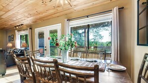 A dining area with a wooden table, chairs, and a vase of flowers.