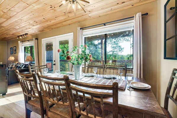 A dining area with a wooden table, chairs, and a vase of flowers.