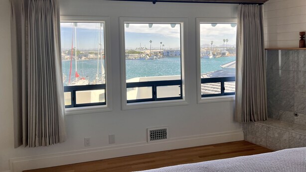 A room with a wooden ceiling, a large window with curtains, a marble wall, and a wooden floor. - Luxury waterfront! The Pagoda Beach House (Oxnard)