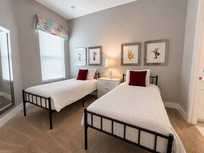Un dormitorio con dos camas, una mesita de noche, una lámpara y decoración en la pared.