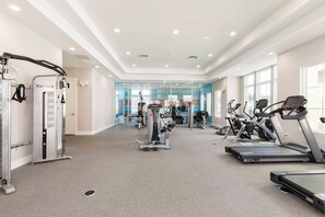 A gym with treadmills, weight machines, and a mirrored wall.