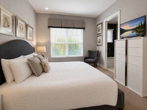A bedroom with a bed, a chair, a dresser, and a painting on the wall.
