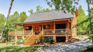 Eine Holzhütte mit Veranda, Treppe und überdachtem Bereich.