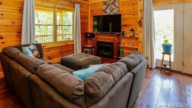 Ein gemütliches Blockhaus-Interieur mit einer Sofagarnitur, einem Kamin und einem Fernseher.