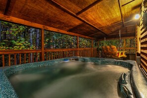 Un espace avec un bain à remous, doté d’une terrasse en bois et entouré d’arbres.