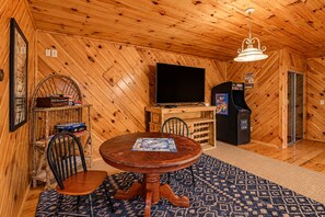 A cozy cabin interior with a wooden ceiling, a dining table with chairs, a television, and a jukebox. - Free Dollywood Tix/Views/Pool/Spacious/Arcade (Sevierville)