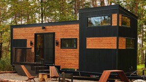 Eine moderne Holzhütte mit großen Fenstern und einer Terrassenfläche mit Sitzgelegenheiten.