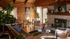 Ein gemütliches Blockhaus-Interieur mit Kamin, Holzwänden und bequemen Sitzmöglichkeiten.