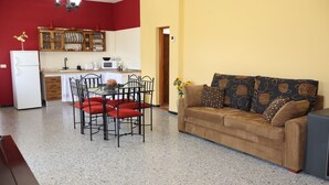 A compact living space with a kitchenette, dining area, and a sofa with patterned cushions. - Casa Rural en San Mateo, con Finca Propia (CN)