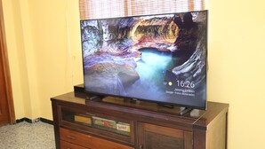 A flat-screen TV on a wooden cabinet with a rocky landscape wallpaper. - Casa Rural en San Mateo, con Finca Propia (CN)