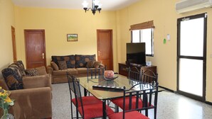A living room with a sofa, a dining table with chairs, a TV, and a large window. - Casa Rural en San Mateo, con Finca Propia (CN)