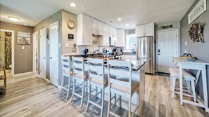 A modern kitchen with a central island, white cabinetry, and a built-in oven.