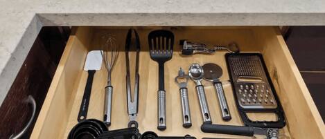 A drawer with various kitchen utensils including a whisk, spatula, and grater.