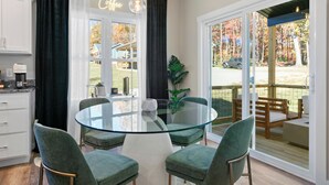 A modern kitchen with a glass dining table, green upholstered chairs, and a coffee sign. - 10 Mins to Downtown Deck w/ Fire Pit Modern Haven Bradford by Avantstay (Asheville)