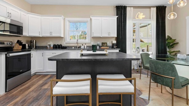 A modern kitchen with white cabinets, a central island with stools, a dining area with a glass table, and a view of the outdoors through a window. - 10 Mins to Downtown Deck w/ Fire Pit Modern Haven Bradford by Avantstay (Asheville)