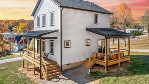 A two-story house with a covered porch and a staircase leading to the entrance. - 10 Mins to Downtown Deck w/ Fire Pit Modern Haven Bradford by Avantstay (Asheville)
