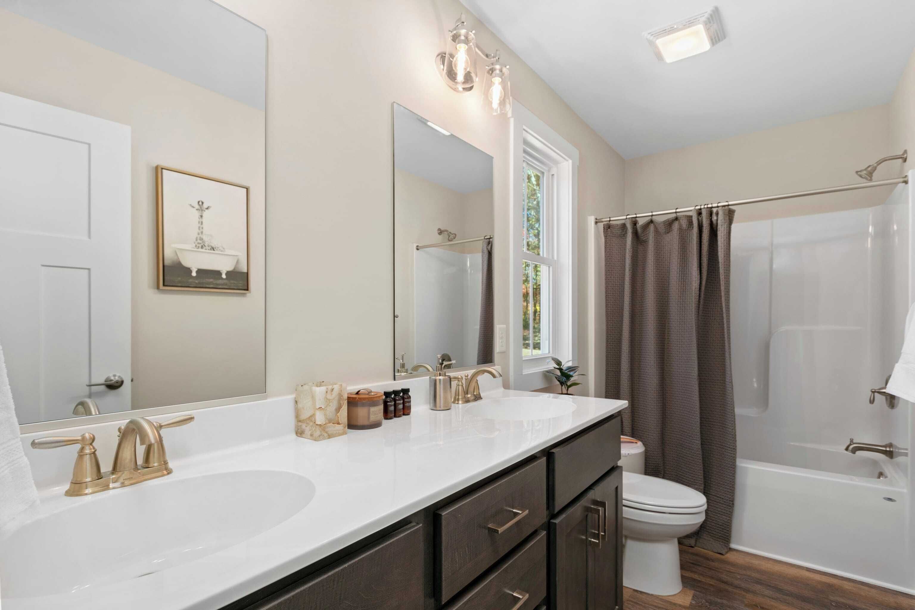 A bathroom with a double sink, a toilet, a bathtub, and a shower.