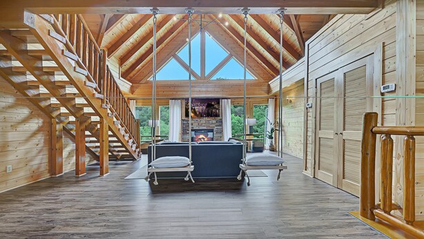 Une cabane en bois spacieuse, dotée d’un plafond de style « loft », d’une cheminée et d’un escalier.