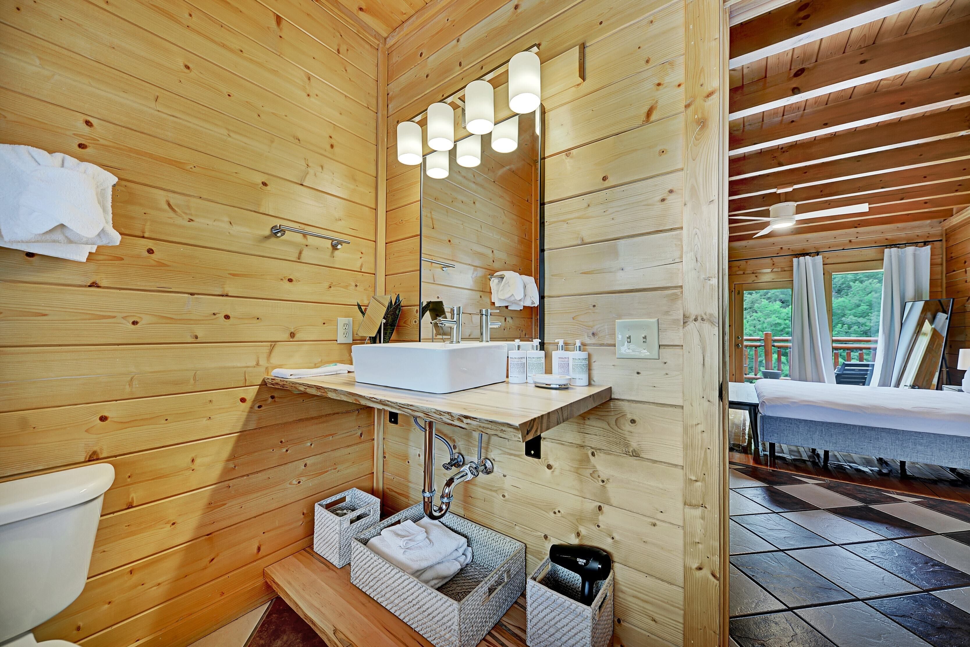 A wooden cabin bathroom with a sink, mirror, and towel storage.