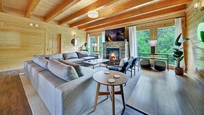 Un intérieur chaleureux de chalet en bois, avec une cheminée, un grand canapé et un coin repas.