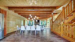 Un intérieur spacieux en bois, comprenant un coin repas, un escalier en bois et une cheminée.