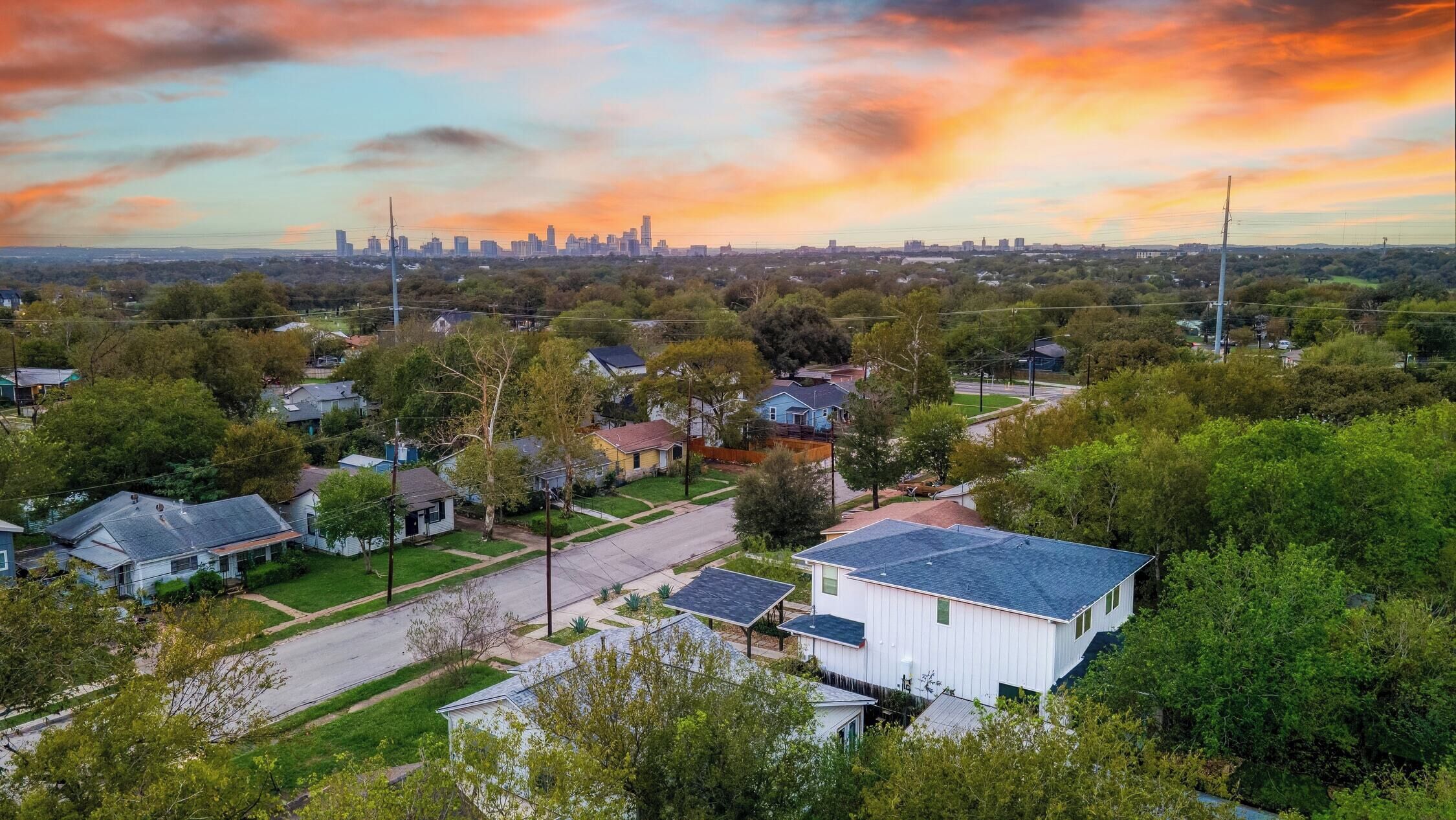 A residential area with houses, a clear sky, and a distant city skyline.