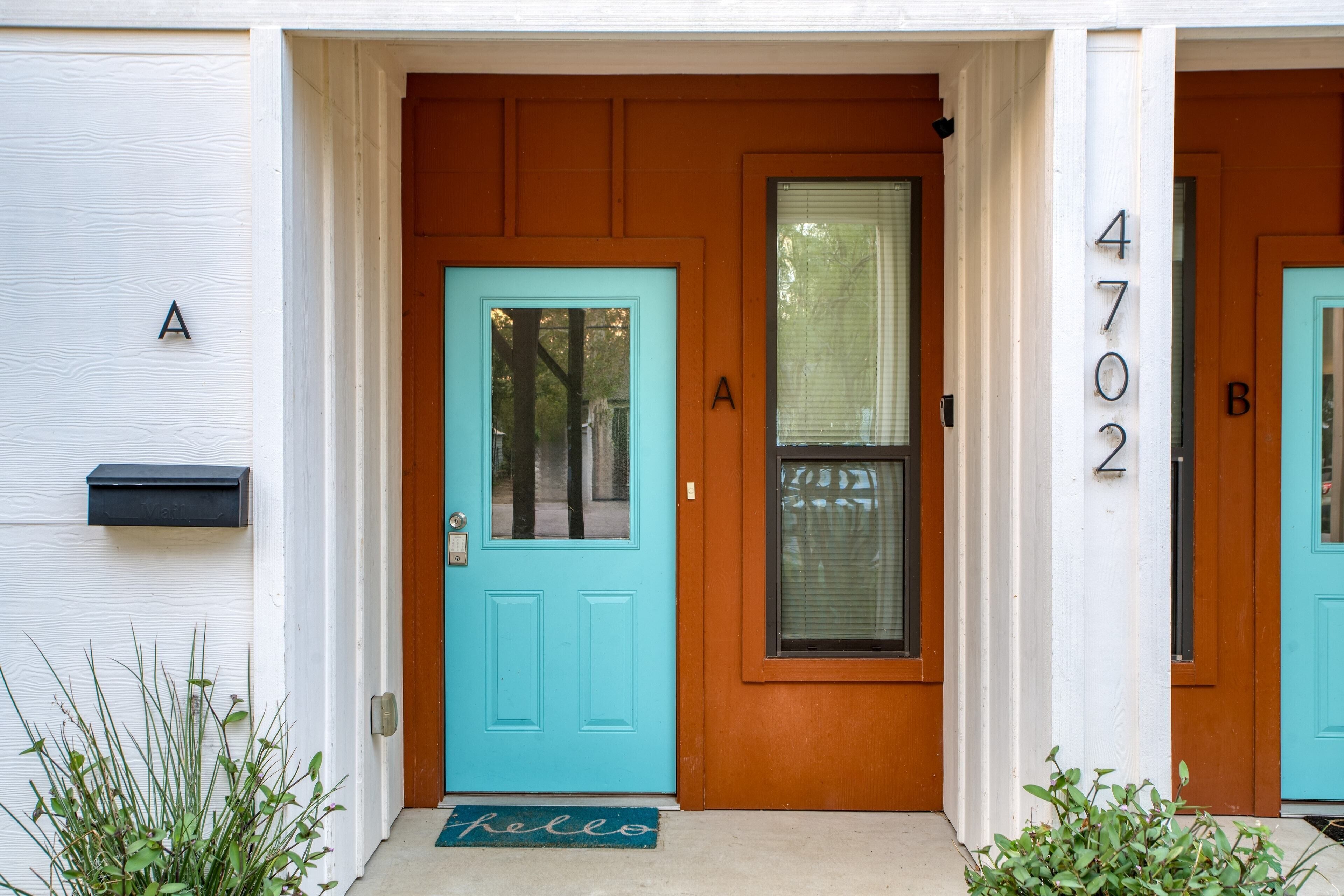 Een huis met een turquoise voordeur, een brievenbus en een 'hello'-mat.