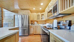 A modern kitchen with wooden cabinets, stainless steel appliances, and a marble countertop. - Scarlet Lodge by Avantstay Game Room + Views (Sevierville)