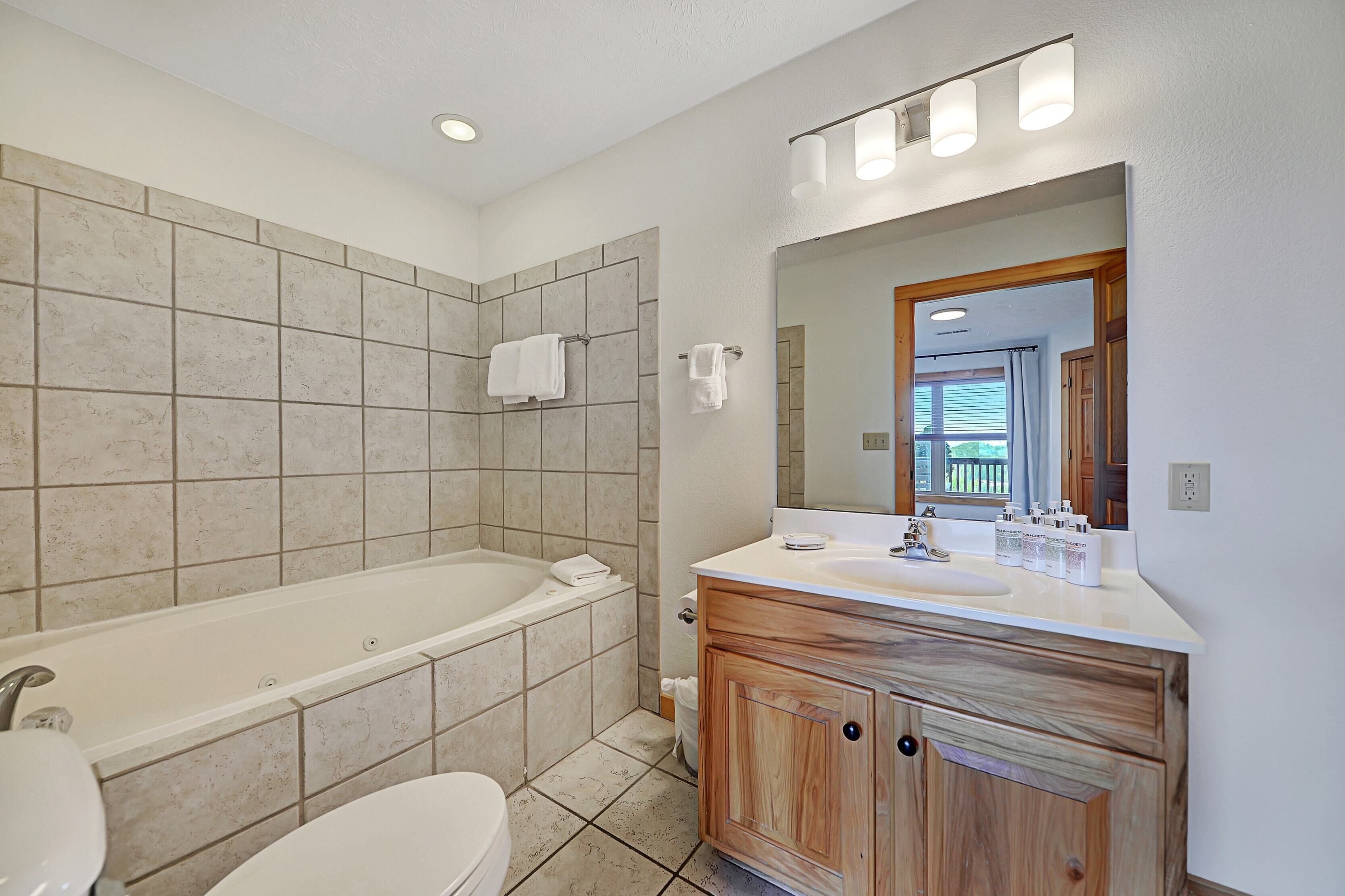 A modern bathroom with a bathtub, toilet, and vanity with a mirror.