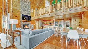 A spacious log cabin interior with a large living area, a fireplace, a dining table, and a balcony. - Scarlet Lodge by Avantstay Game Room + Views (Sevierville)
