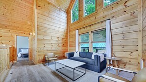 A wooden cabin interior with a sofa, coffee table, and chairs. - Scarlet Lodge by Avantstay Game Room + Views (Sevierville)