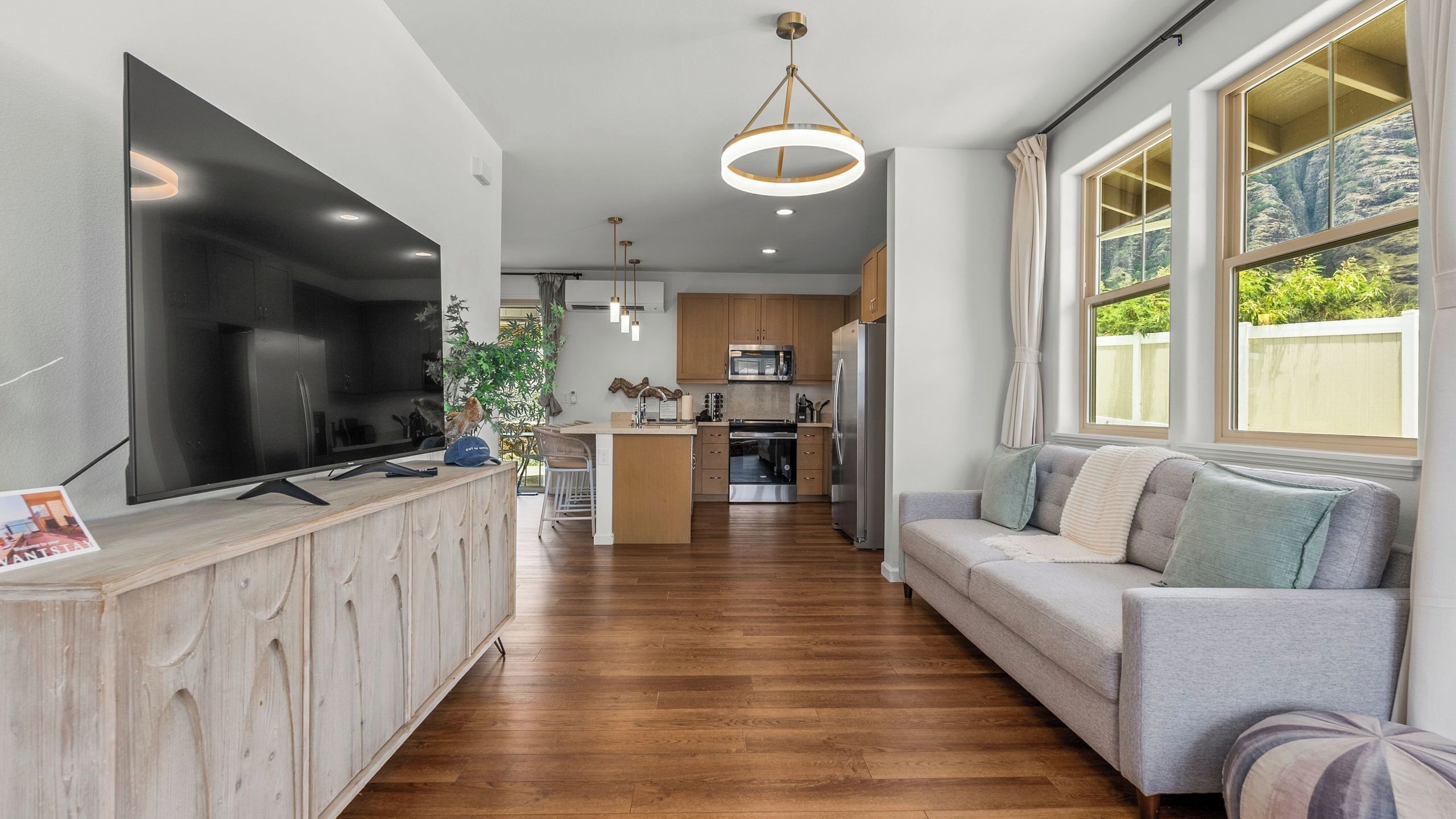A modern kitchen with a large TV, wooden cabinets, and a central island.
