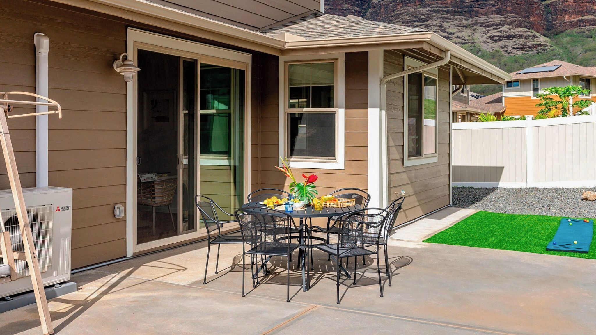 A patio with a table and chairs, a Mitsubishi Electric air conditioner, and a view of a neighboring house.