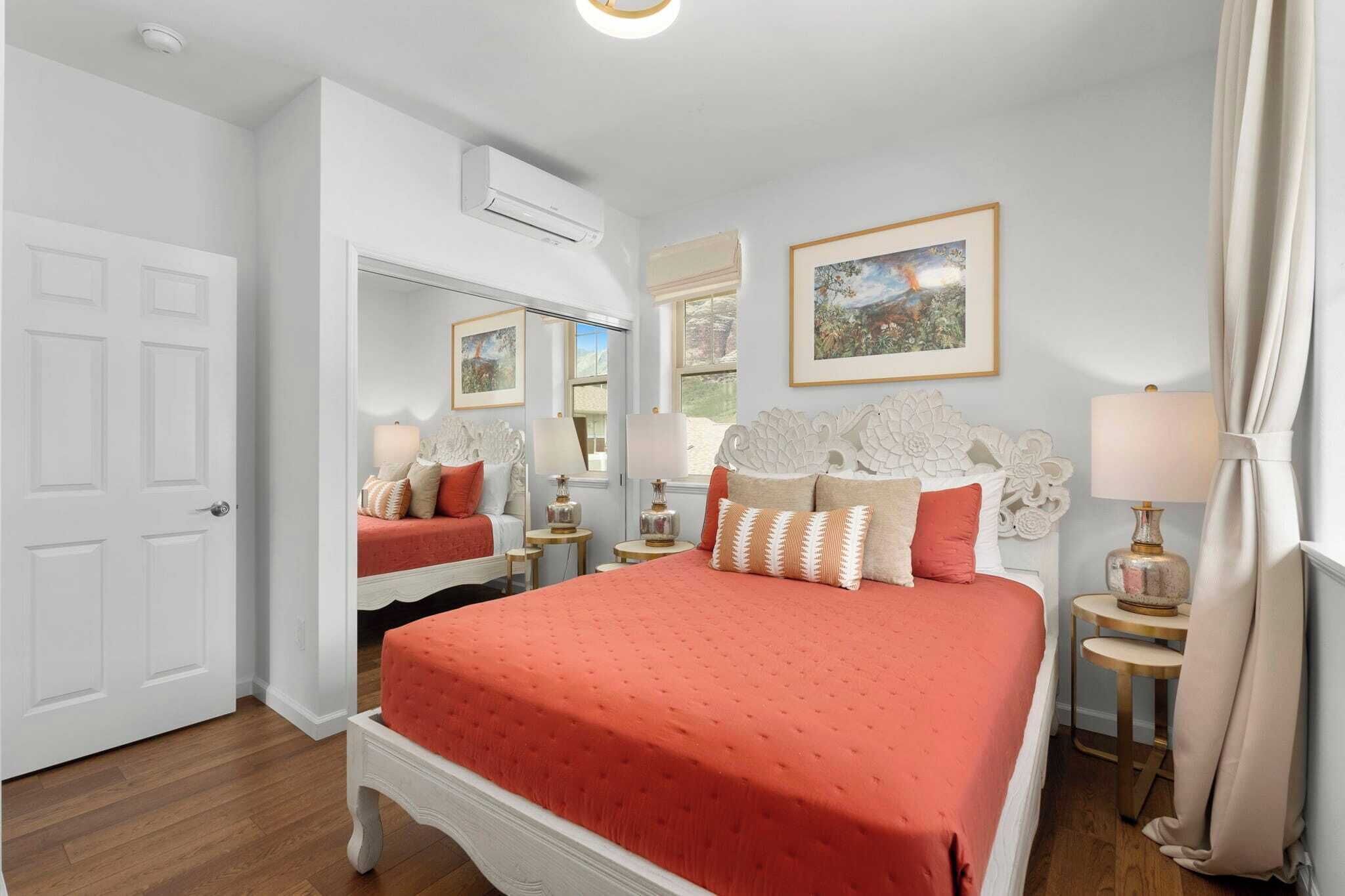 Une chambre à coucher avec un grand lit, deux tables de chevet, un miroir et une fenêtre avec des rideaux.