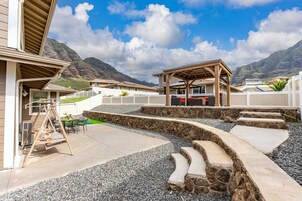 Zona residencial con patio, un columpio y un espacio de estar techado con vistas a las montañas.