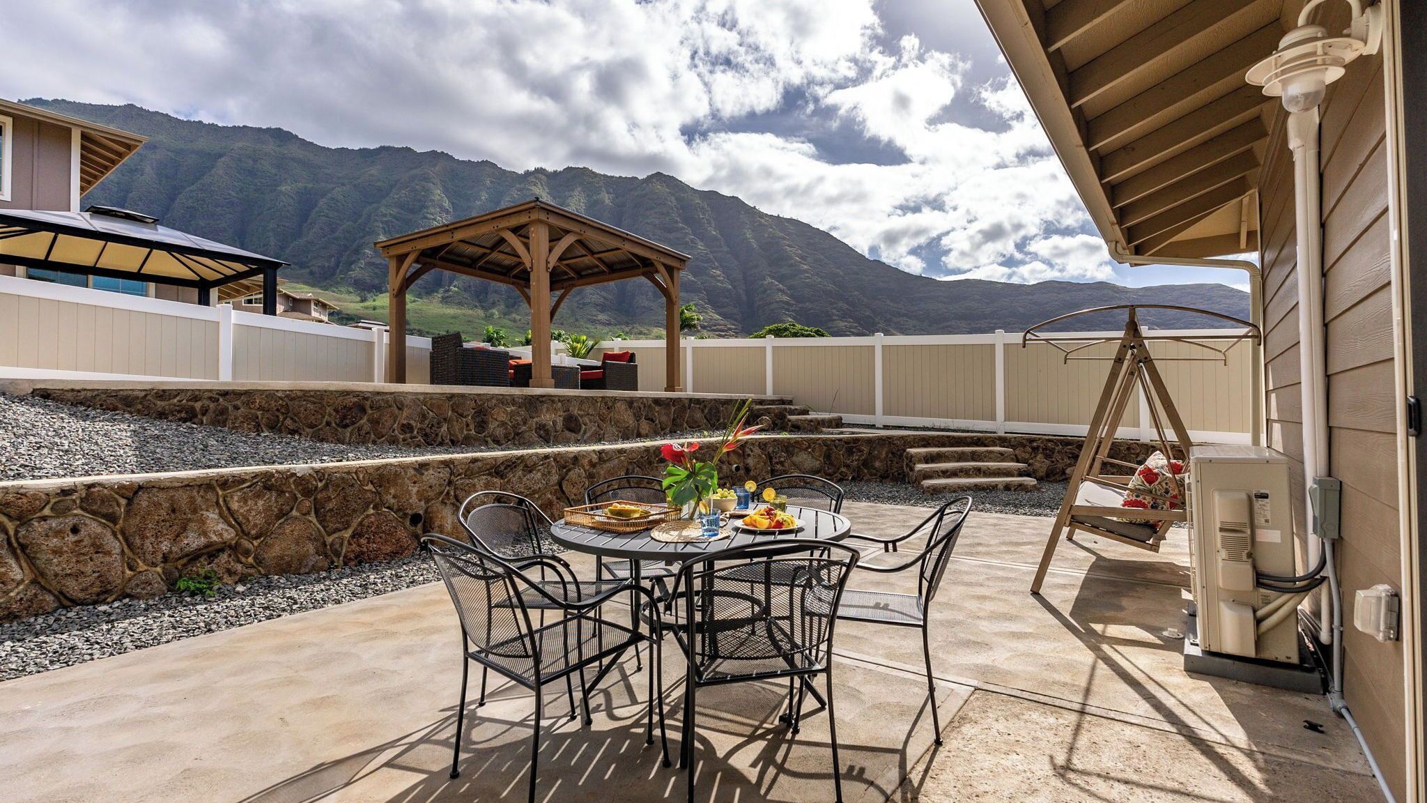 Une terrasse extérieure avec une table et des chaises, une pergola et une vue sur la montagne.